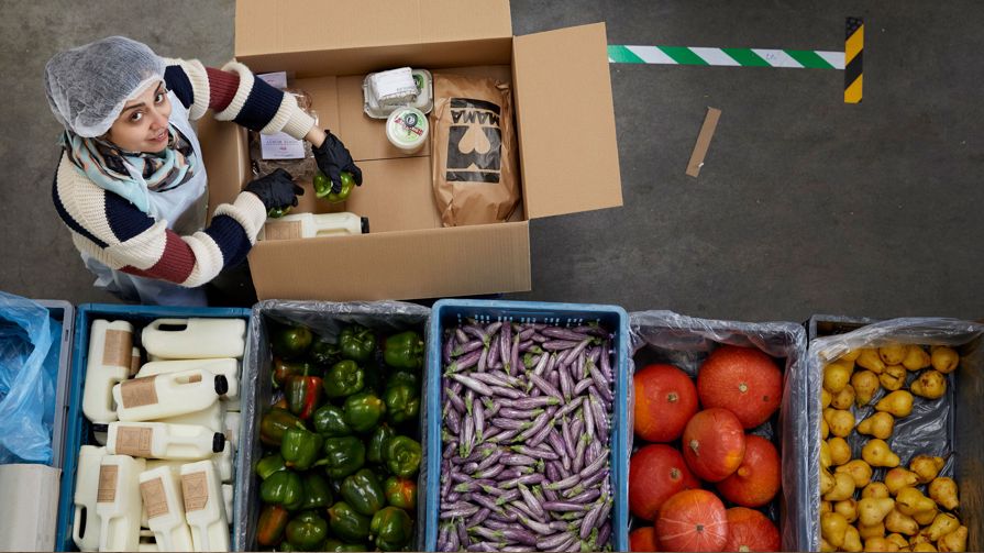 A voulenteer packing a food box with vegetables