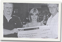 Dennis Williams yn derbyn siec gan Arfon Wlliams a Liz Lewis ar ran y cyngor bro.