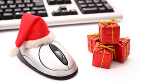 A computer mouse decorated with a Santa hat, beside a small gift, illustrating online shoppin