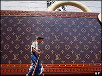 Một người nhặt rác đi ngang mô hình quảng cáo túi thời trang nổi tiếng Louis Vuitton tại Thượng Hải