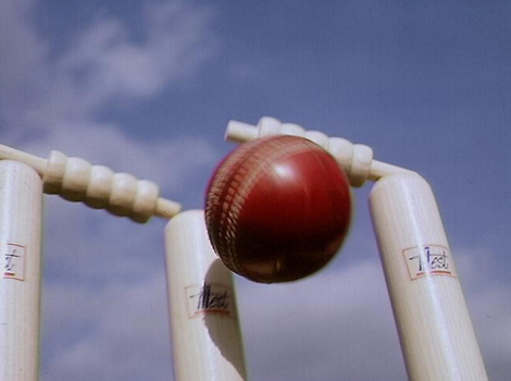 A cricket ball hitting stumps