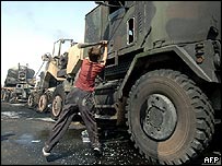 Menino iraquiano ataca um veículo americano bombardeado em Bagdá.