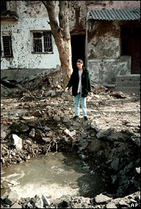 Mulher mostra cratera em frente a sua casa em Grozny