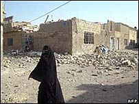 Mulher caminha entre os escombros na região de Cidade Sadr