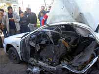 Palestinos observam carro atingido por míssil israelense na Faixa de Gaza