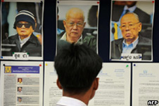 A Cambodian man looks at pictures of former Kmer Rouge leaders Nuon Chea (L), Khieu Samphan (middle) and Ieng Sary (R)