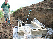 Man standing beside half-built otter holt