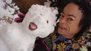 Liz Carr smiling next to her toothy snowman