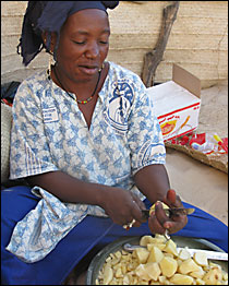 Madame Djambaro chops piles of potatoes