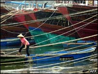 Mulher amarra barco em Hainan, antes da chegada do tufão