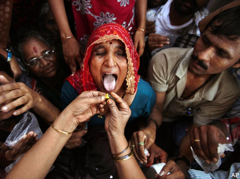 A woman opens her mouth to receive 'fish medicine'.