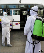 Funcionários chineses desinfetam ônibus