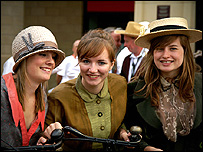 Three girls dressed up with old fashioned cycles