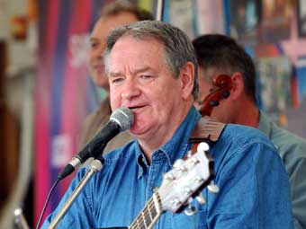 Dafydd Iwan ar faes yr Eisteddfod yn diddanu'r dorf.