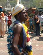 Man in colourful garlands, with tiny silvery pots hooked into his skin