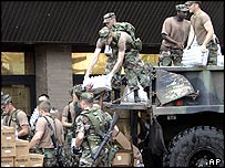 سربازان بطری های آب آشاميدنی را به مناطق آسيب ديده منتقل می کنند