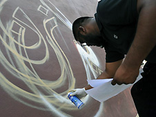 Man spraying cream paint onto light brown wall