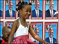 دختربچه ای در موزامبيک از برابر پوسترهای تبليغاتی می گذرد