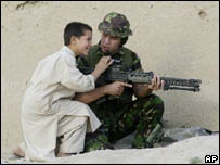 Garoto afegão tenta olhar na mira da arma de soldado britânico, em Cabul