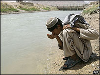 Menino afegão bebe água diretamente de rio em Kandahar