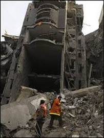 Các nhân viên cứu hoả người Palestine xem xét một khu nhà bị không kích tại Gaza City hôm 30.12.08