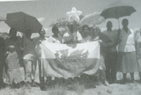 Helen Davies yn chwifio baner Cymru gyda staff ysgol yn Lesotho.