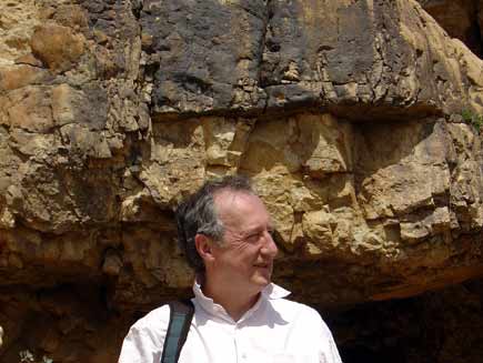 Roger Bolton stands in front of a low cave mouth