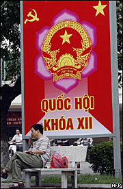 Người dân ngồi trước áp phích cổ động bầu cử