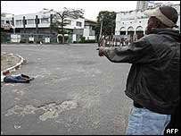 Homem olha cadáver em rua de Kinshasa