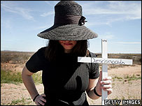 يکی از معترضان به برنامه 'حاضر به خدمت' صليبی را به نشانه يکی از مهاجرانی که هنگام ورود به آمريکا جان باخته اند به دست دارد