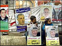 زن های فلسطينی از برابر پوسترهای انتخاباتی عبور می کنند