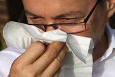 A man blowing his nose on a tissue