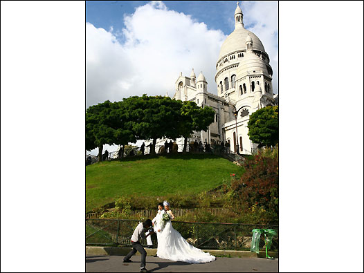一对中国年轻夫妇在蒙玛特的圣心堂下拍摄婚纱照。