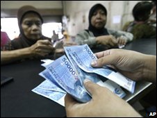 Một phụ nữ đứng phân phát phiếu trợ giá xăng dầu cho các đối tượng là người nghèo.