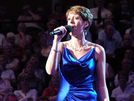 Connie Fisher, in blue evening dress, singing on stage