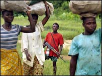 Soldado da Libéria observa civis que saem para vender mandioca no interior do país