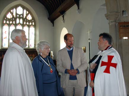 Martin Palmer, third from left, talking to  three people.  The two other men wear traditional Templar mantles, white with a red splayed cross visible on one side, and the woman is wearing the same red cross symbol around her neck