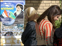 चुनावी पोस्टर पढ़ती इराक़ी महिला