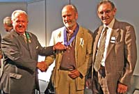 Iolo yn derbyn y fedal gan Lywydd yr Eisteddfod, Huw Thomas, yng nghwmni'r Archdderwydd, Dic Jones.