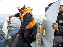 کارکن سمندر سے جہاز ملبہ نکال رہے ہیں