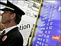 یک خلبان اعتصابی کنار تابلوی راهنمای پرواز در فرودگاه زوریخ