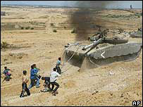 Jovens palestinos jogam pedras em tanques israelenses