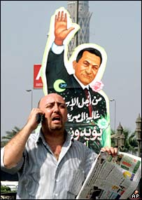 يک مرد مصری در حال عبور از مقابل يک تابلوی تبليغاتی با تصوير حسنی مبارک