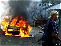 Soldado australiano passa em frente a casa incendiada na capital, Dili