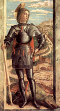 George stands, armoured and helmetless, holding a broken spear, the missing end of which is visible stuck in the mouth of the dead dragon at his feet. Behind him is a grand city on a hill