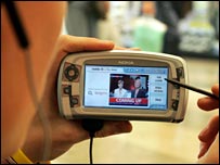 Homem assiste TV pelo celular