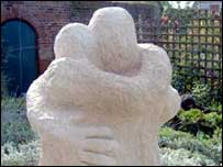 A sculpture of two people hugging in a garden.