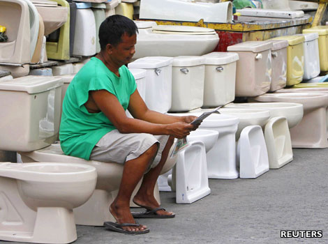 A Filipino man takes a seat on a second-hand toilet bowl he is selling.
