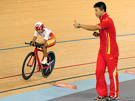 Sini Zeng of China cycles past her coach as he gives the thumbs up during the London 2012 Paralympic Games.