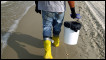 A contract worker hired by BP patrols the shore for oil to collect. Getty